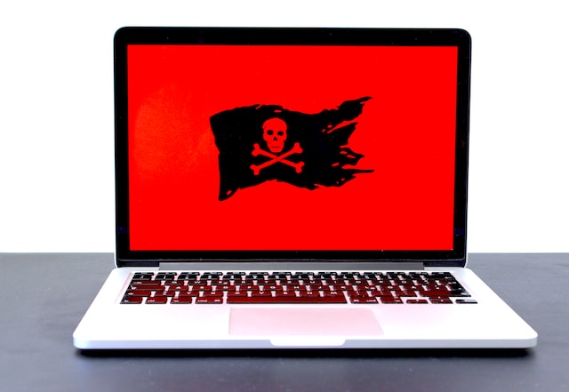 A laptop displaying a jolly roger pirate flag on a red background.